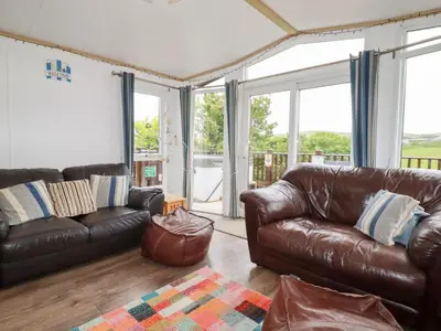 a living room with leather furniture and large windows at Orchard View in Tintagel