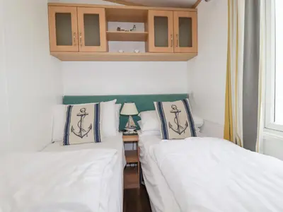 two beds in a room with a table with a lamp at Orchard View in Tintagel