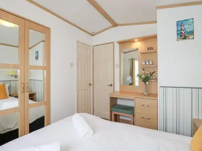 a bedroom with a bed and a desk and a mirror at Orchard View in Tintagel