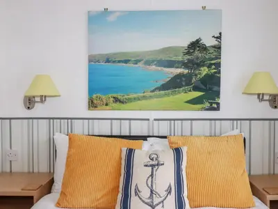 a bedroom with yellow pillows and a painting on the wall at Orchard View in Tintagel