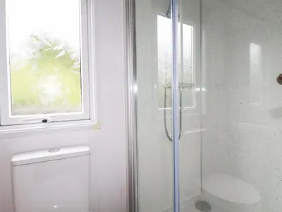 a bathroom with a shower and a toilet and a window at Orchard View in Tintagel