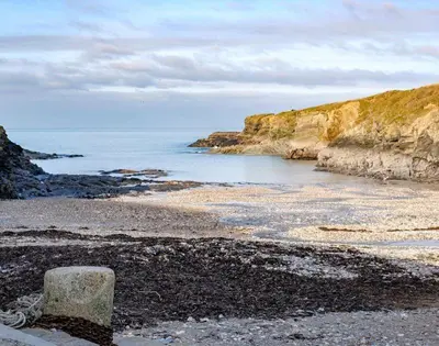 a rock sitting on a beach next to the ocean at Stop Tide in Port Isaac