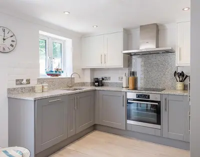 a kitchen with white cabinets and a clock on the wall at Stop Tide in Port Isaac