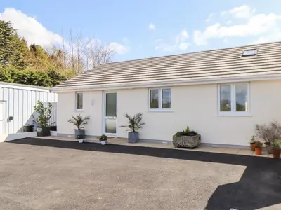 a white house with potted plants in front of it at Chy-Whel in St Austell
