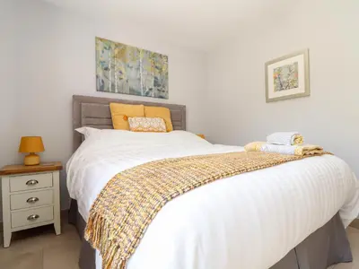 a bedroom with a bed with white sheets and orange pillows at Chy-Whel in St Austell