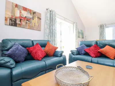 a living room with a blue couch with colorful pillows at Chy-Whel in St Austell