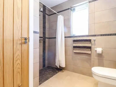 a bathroom with a shower with a toilet and a window at Chy-Whel in St Austell