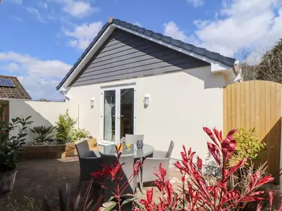 a small white house with a table and chairs at Chy-Whel in St Austell