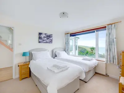 two beds in a bedroom with a window at Shilling Stones in Port Isaac