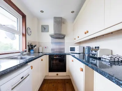 a kitchen with white cabinets and black counter tops at Shilling Stones in Port Isaac