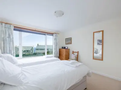 a bedroom with two beds and a large window at Shilling Stones in Port Isaac