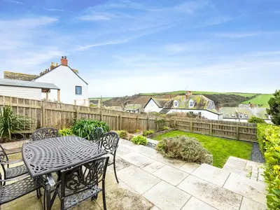 a patio with a table and chairs and a fence at Shilling Stones in Port Isaac