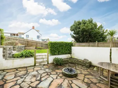 a patio with a fire pit and a fence at Shilling Stones in Port Isaac