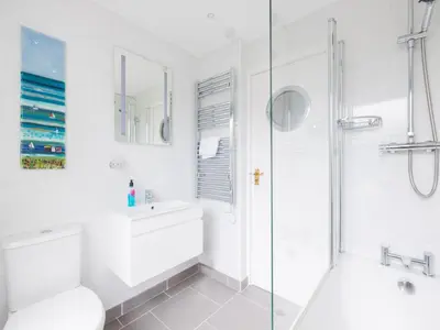 a white bathroom with a shower and a sink at Shilling Stones in Port Isaac