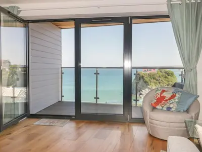 a living room with sliding glass doors and a chair at Onshore in Newquay