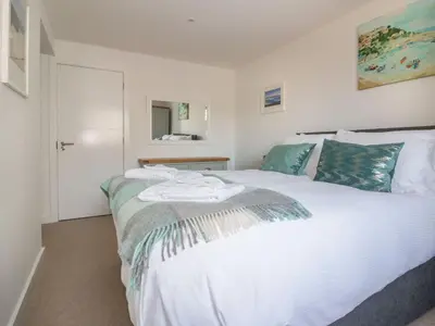 a bedroom with a bed with white sheets and blue pillows at Onshore in Newquay