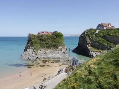 a beach with a house on top of a cliff at Onshore in Newquay