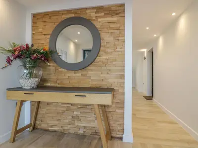 a mirror on a wall next to a table with flowers at Fistral Watch in Newquay
