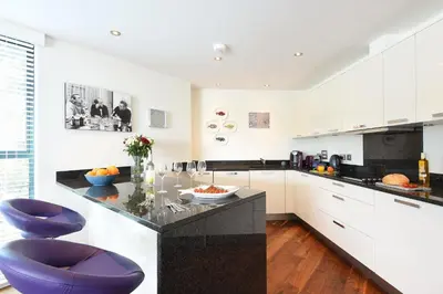 a kitchen with white cabinets and a blue chair at The Boats in St Ives