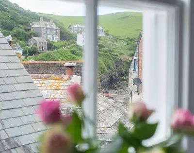 a view of a house from a window with flowers at Bre Cottage in Port Isaac