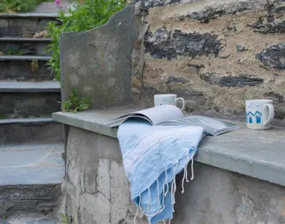 a book and coffee cups on a stone ledge at Bre Cottage in Port Isaac