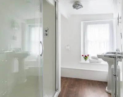 a white bathroom with a shower and a sink at Bre Cottage in Port Isaac