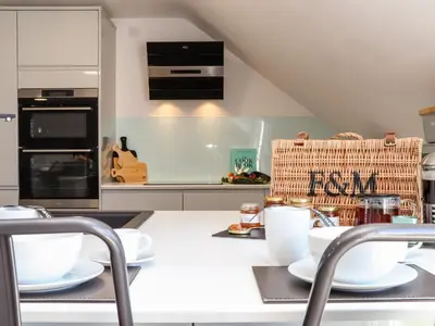 a kitchen with a white counter top with dishes on it at Penthouse 23 in Newquay