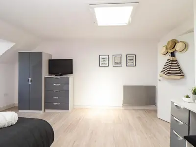 a bedroom with a bed and a dresser with a television at Penthouse 23 in Newquay