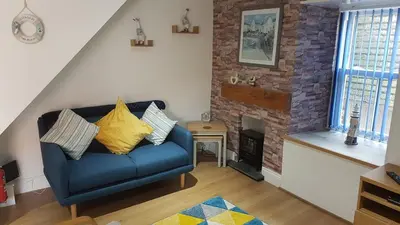 a living room with a blue couch and a fireplace at Cheerful Fisherman,s Cottage in St Ives