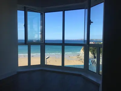 a room with windows looking out at a beach at The Towan Lookout in Newquay