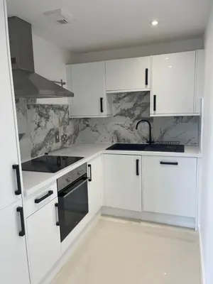 a white kitchen with white cabinets and a sink at The Towan Lookout in Newquay