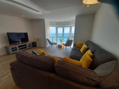 a living room with a brown couch and a television at The Towan Lookout in Newquay