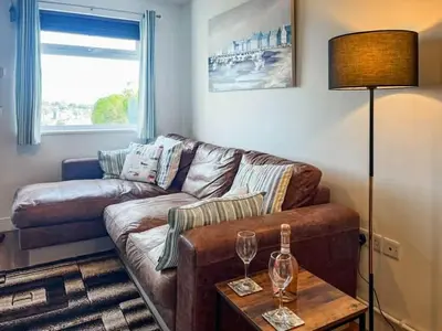 a living room with a couch and a table with wine glasses at Hillside in St Austell