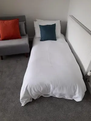 a bed with two pillows and a couch in a room at Bosloe in Helston