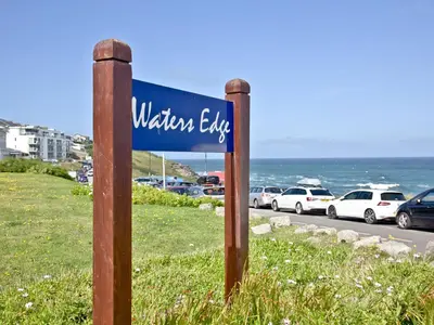 a blue sign for the wilsons elite on a beach at Apartment 1 Waterrs Edge in Crantock