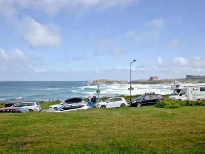 a group of cars parked next to the ocean at Apartment 1 Waterrs Edge in Crantock