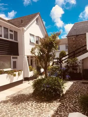 a house with a palm tree in a courtyard at Island View - 3 Bedroom Holiday Cottage - 40m to Porthgwidden Beach - Sleeps 7 - inc FREE Parking in St Ives