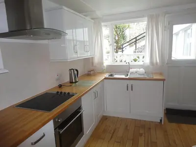 a kitchen with white cabinets and a stove top oven at Island View - 3 Bedroom Holiday Cottage - 40m to Porthgwidden Beach - Sleeps 7 - inc FREE Parking in St Ives