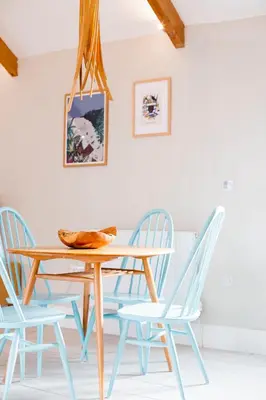 a dining room with a wooden table and blue chairs at Sleepers Barn in Saint Teath