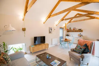 a living room with a couch and a table at Sleepers Barn in Saint Teath