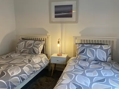 a bedroom with two beds and a lamp on a night stand at Saffron in Saint Columb Minor