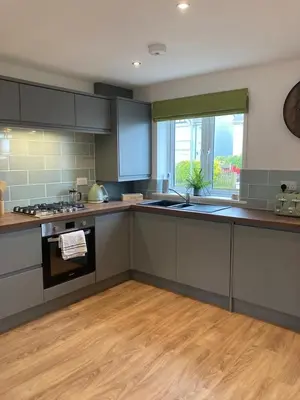 a kitchen with gray cabinets and a wooden floor at Saffron in Saint Columb Minor