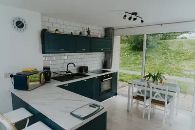 a kitchen with green cabinets and a table with chairs at Newquay Holiday Home in Newquay
