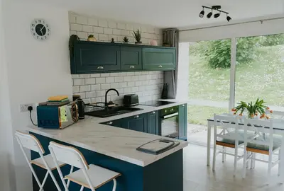 a kitchen with green cabinets and a table and chairs at Newquay Holiday Home in Newquay