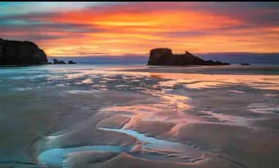 a sunset on a beach with the ocean at Romantic hideaway, seconds away from Perran beach in Perranporth