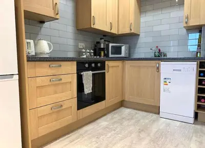 a kitchen with wooden cabinets and a white refrigerator at Romantic hideaway, seconds away from Perran beach in Perranporth