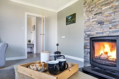 a living room with a fireplace and a table with croissants at Venn Down Lakes in Boscastle