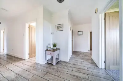 a hallway with white walls and a table on a tile floor at Venn Down Lakes in Boscastle