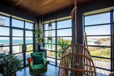 a room with large windows and a green chair at Chy conary in Carbis Bay
