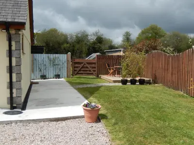 a backyard with a wooden fence and a patio at Rockley Cottage, close to Eden project and Fowey. in Bodmin